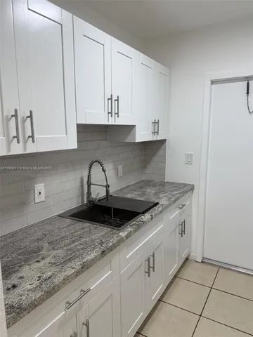 a kitchen with granite countertop white cabinets and a sink