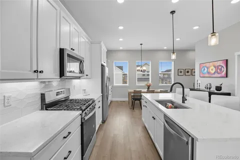 a large kitchen with stainless steel appliances granite countertop a sink a stove and a refrigerator