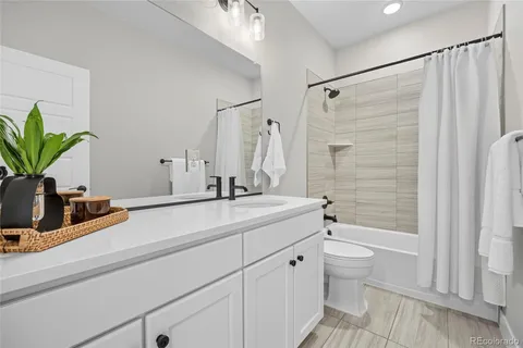 a bathroom with a granite countertop sink a toilet a mirror and shower
