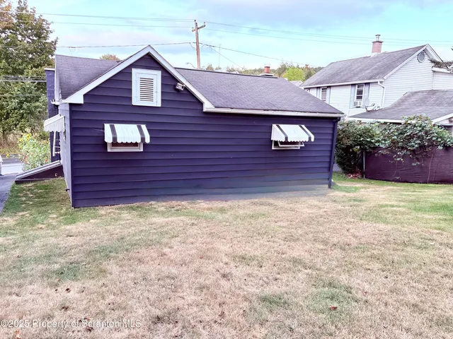 a view of a yard in front of a house with plants and wooden fence