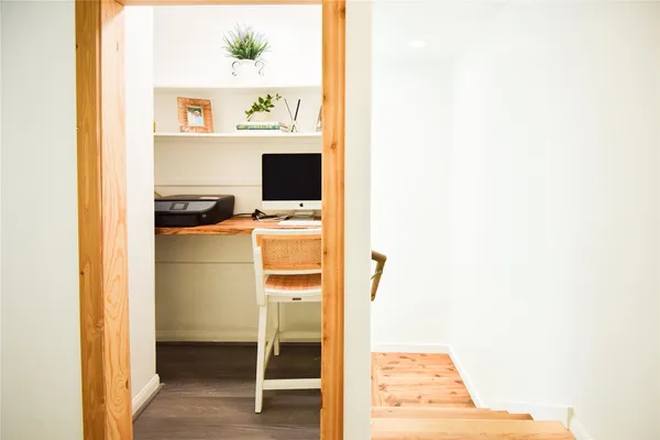 a view of a hallway with wooden floor and a bathroom