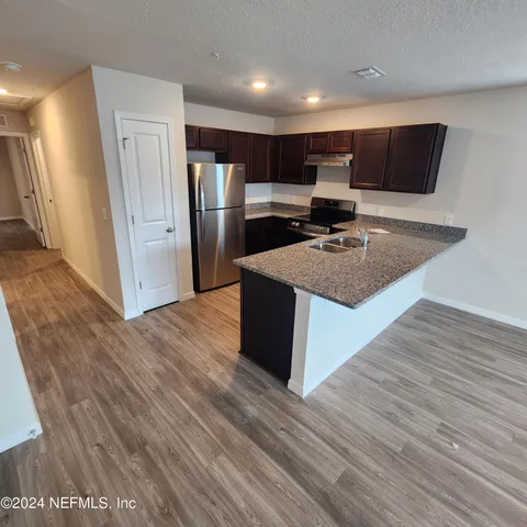 a kitchen with stainless steel appliances kitchen island granite countertop a refrigerator and a sink