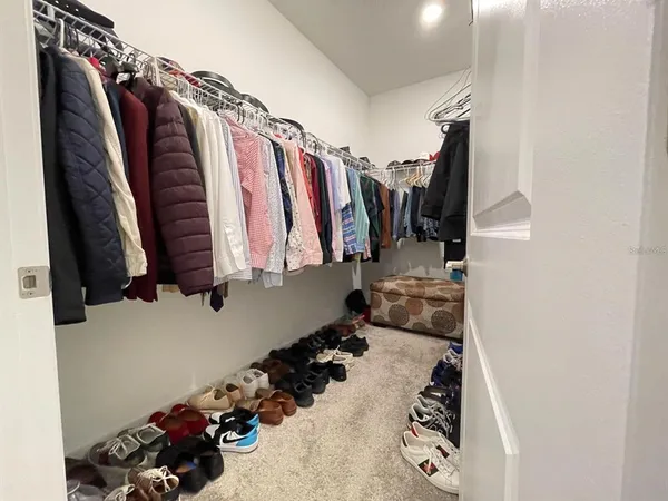 a view of walk in closet with clothes and shoes