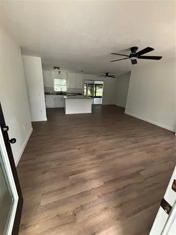 a view of a refrigerator in kitchen and an empty room