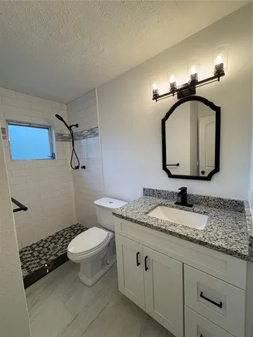 a bathroom with a granite countertop toilet a sink and a mirror