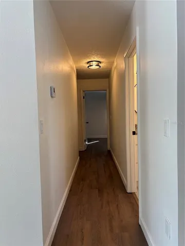 a view of a hallway with wooden floor and a door