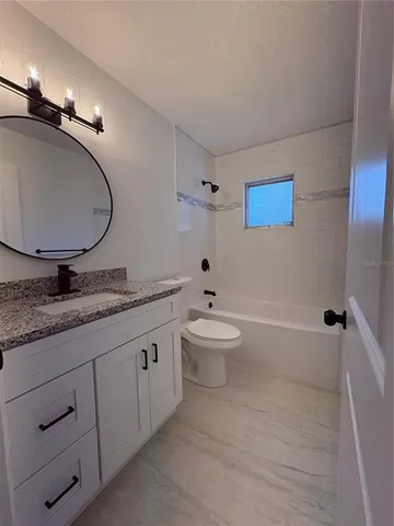a bathroom with a granite countertop sink mirror toilet and bathtub