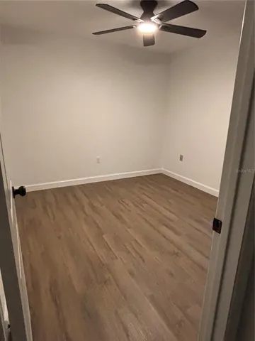 an empty room with wooden floor and fan