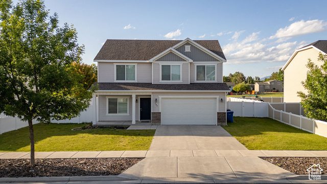 View of front of house featuring driveway, a garage, stone siding, and roof with shingles