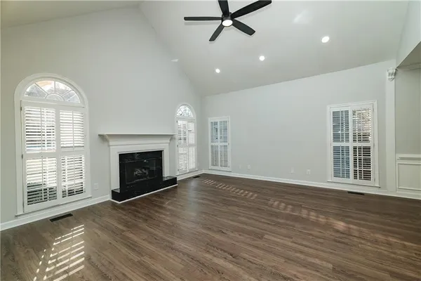 an empty room with wooden floor fireplace and windows