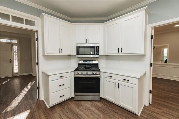 a kitchen with granite countertop white cabinets and stainless steel appliances