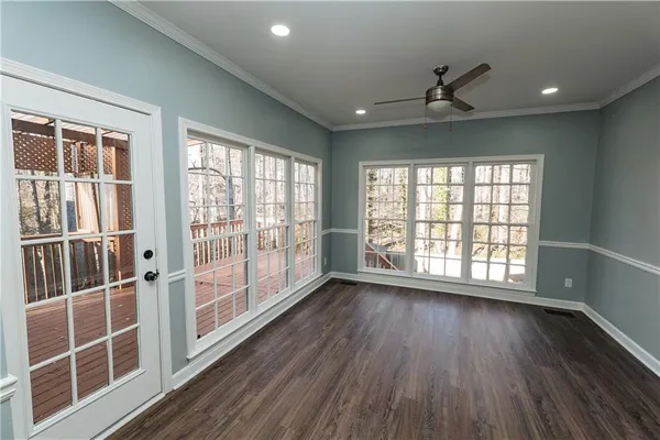 a view of an empty room with wooden floor and a window