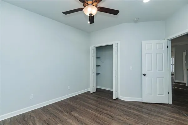 an empty room with wooden floor chandelier fan and closet area