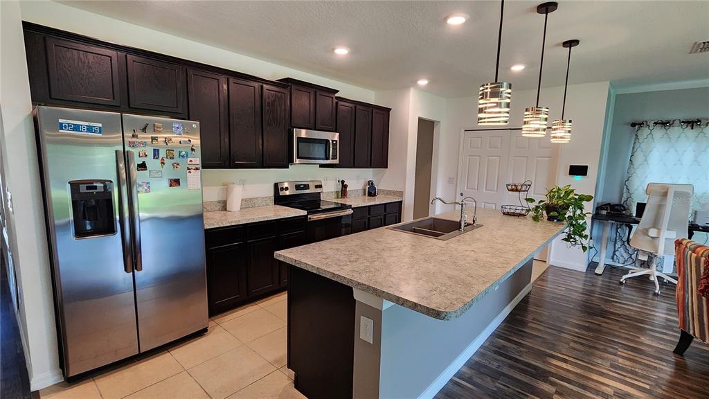 4540 Lake Russell Road Kissimmee, FL 34746 - Photo 25 of 35 a kitchen with stainless steel appliances kitchen island granite countertop a refrigerator dining table and chairs