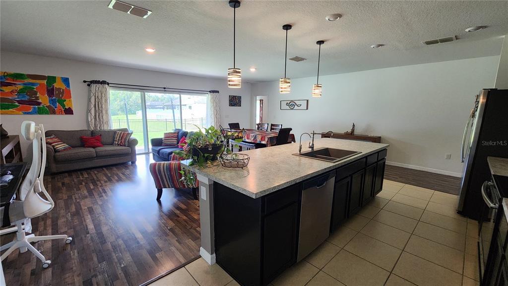 4540 Lake Russell Road Kissimmee, FL 34746 - Photo 26 of 35 a kitchen with a stove a refrigerator a sink dishwasher with a dining table and chairs with wooden floor