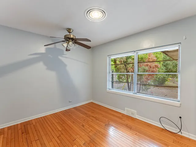 a view of a room with a large window ceiling fan and wooden floor