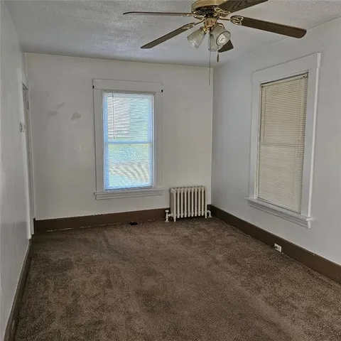 an empty room with windows and fan