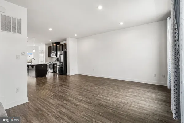 a kitchen with stainless steel appliances granite countertop a refrigerator a sink dishwasher a stove and white countertops with wooden floor