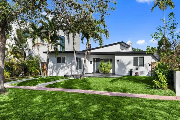 a front view of a house with a garden and trees