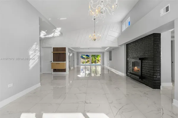 a view of a livingroom with a fireplace a chandelier and windows