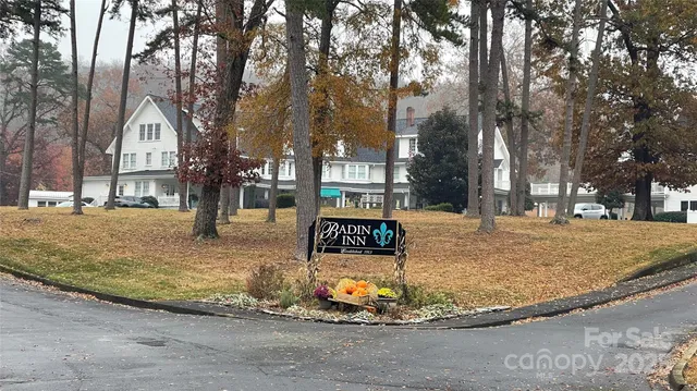 a view of a white house with a yard and large trees