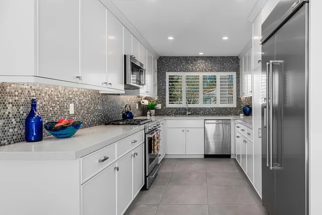 a kitchen with white cabinets and window