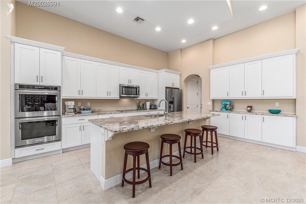 4981 Southeast Inlet Isle Way Stuart, FL 34997 - Photo 21 of 42 a large kitchen with cabinets chairs and a stove