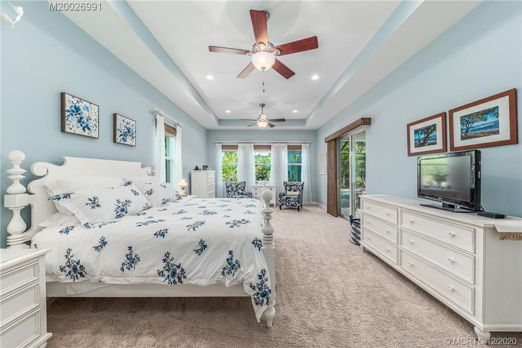 4981 Southeast Inlet Isle Way Stuart, FL 34997 - Photo 28 of 42 a spacious bedroom with a bed and a flat screen tv