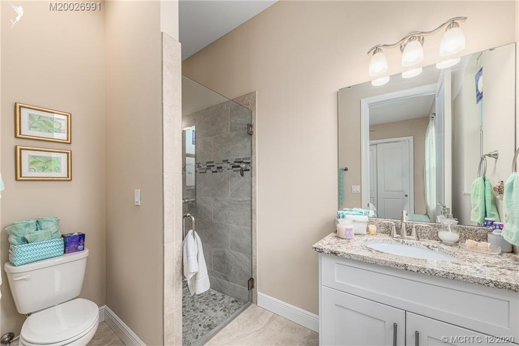 4981 Southeast Inlet Isle Way Stuart, FL 34997 - Photo 33 of 42 a bathroom with a granite countertop sink toilet and shower