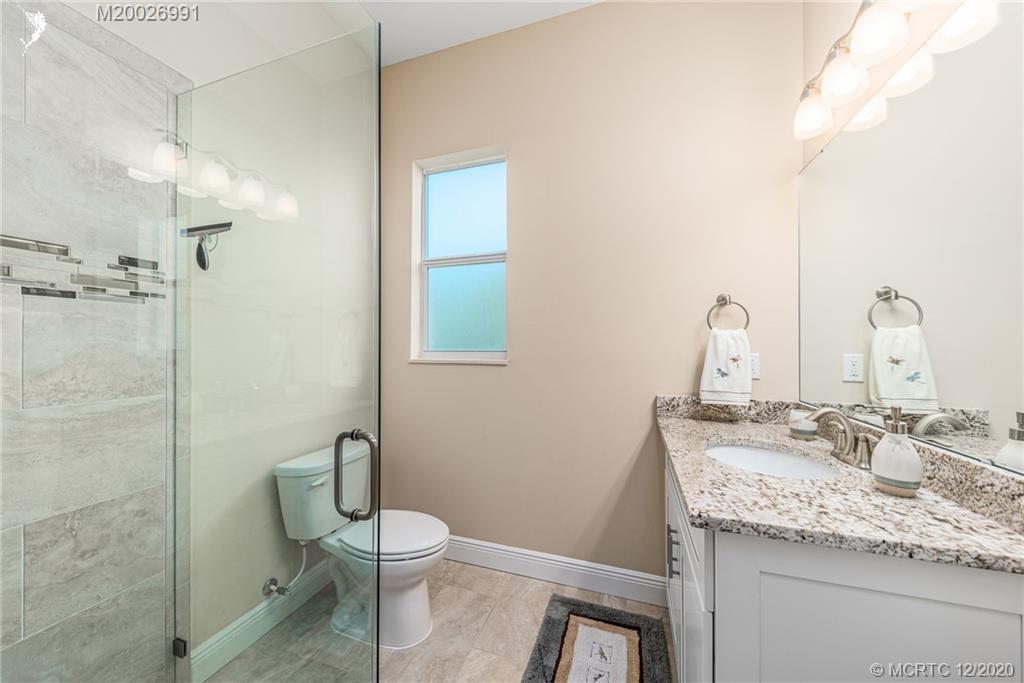 4981 Southeast Inlet Isle Way Stuart, FL 34997 - Photo 35 of 42 a bathroom with a granite countertop sink a toilet and a mirror