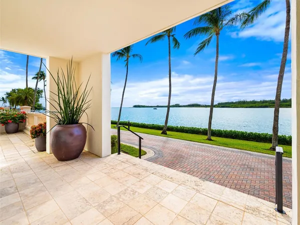 a living room with stainless steel appliances furniture a rug and a kitchen view