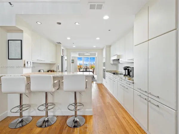 a kitchen with stainless steel appliances granite countertop a stove top oven a sink dishwasher and white cabinets with wooden floor