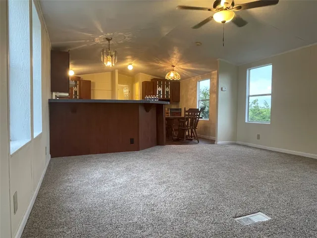 an empty room with chandelier fan and windows