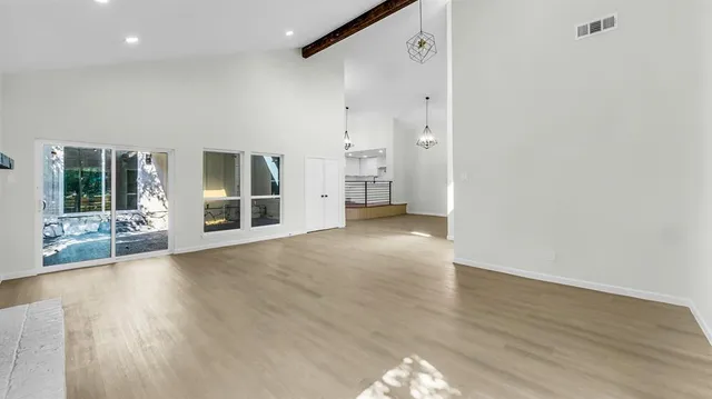 a view of an empty room with wooden floor fireplace and a window