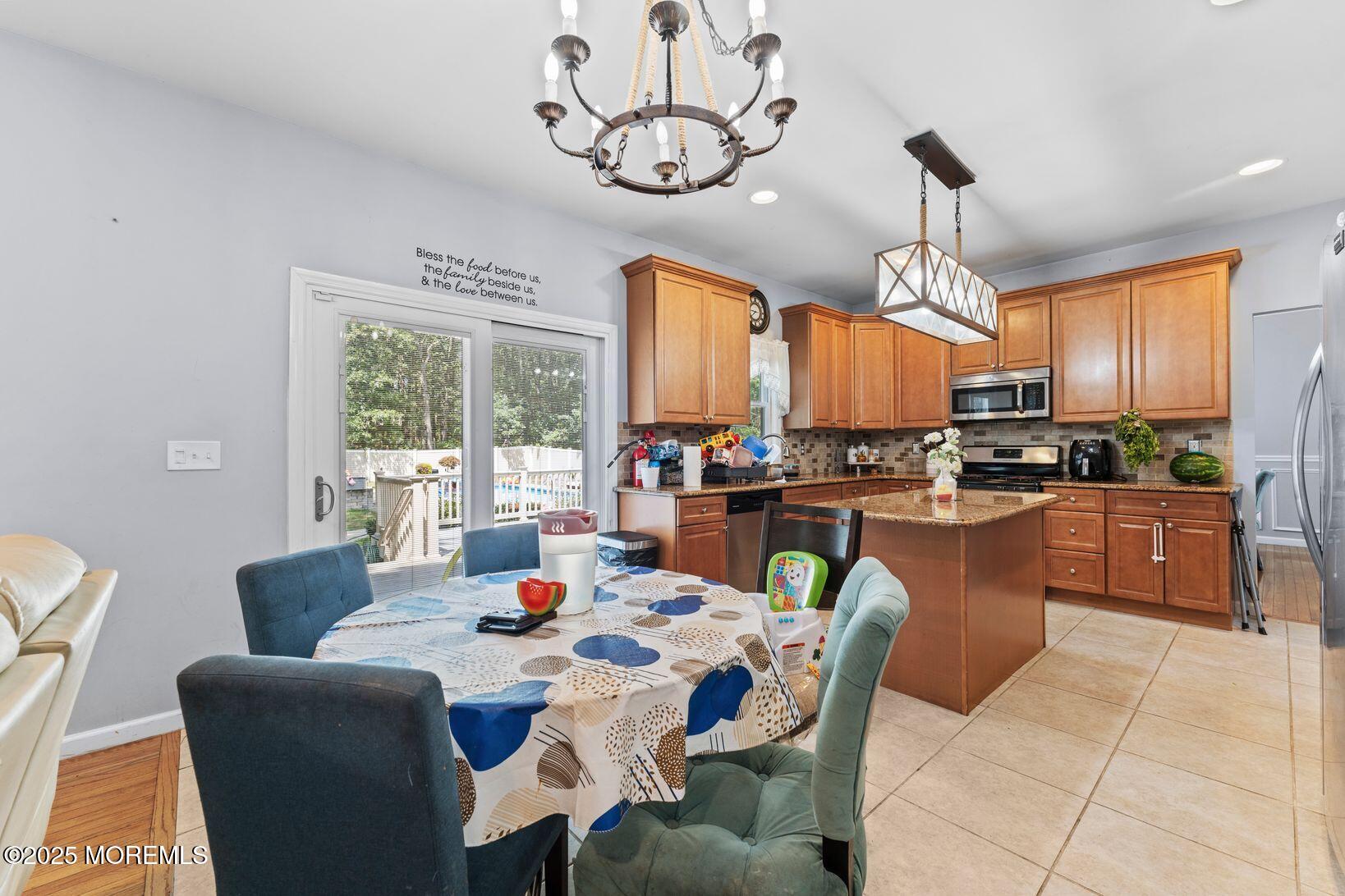 24 Friendship Road Howell, NJ 07731 - Photo 9 of 34 a dining room with stainless steel appliances kitchen island granite countertop a table chairs and a chandelier