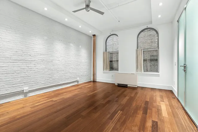 a view of an empty room with wooden floor window and a bathroom