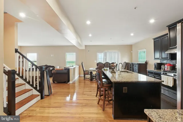 a dining hall with stainless steel appliances granite countertop a sink a table and chairs
