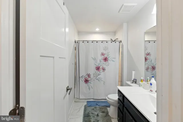 a bathroom with a sink a toilet and shower curtain