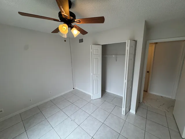 a view of an empty room and chandelier fan