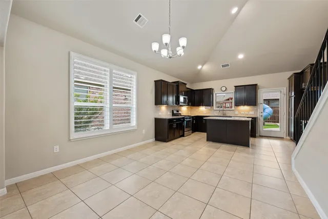 a large white kitchen with a large kitchen island a stove a sink cabinets and a dining table