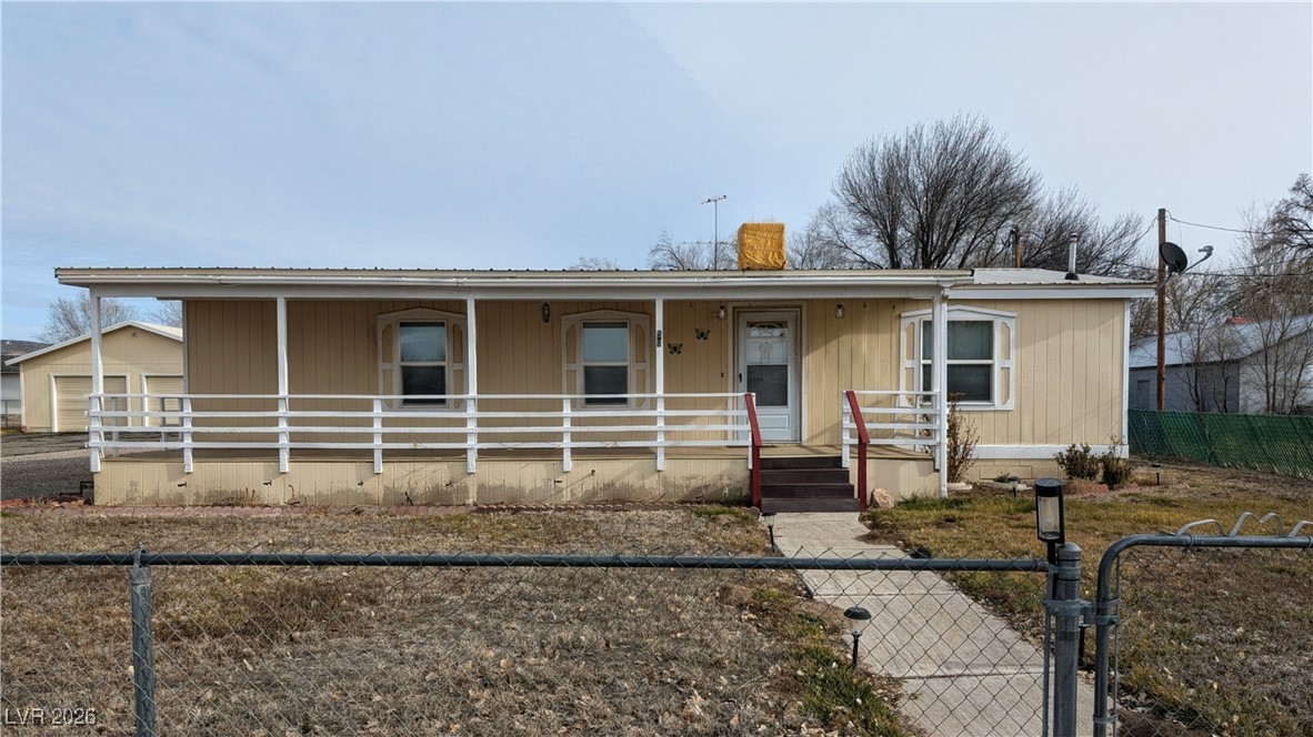 50 North 2nd Street Panaca, NV 89042 - Photo 2 of 35 View of front of home with a fenced front yard, a gate, covered porch, a chimney, and a garage