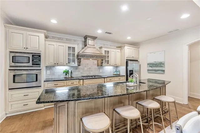a kitchen with stainless steel appliances granite countertop a stove top oven a sink a dining table and chairs