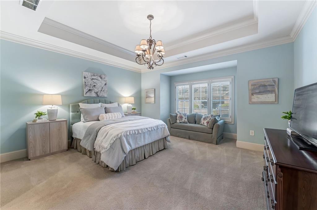 2550 Ballantrae Circle, Unit 53F Cumming, GA 30041 - Photo 18 of 46 a spacious bedroom with a bed and a chandelier