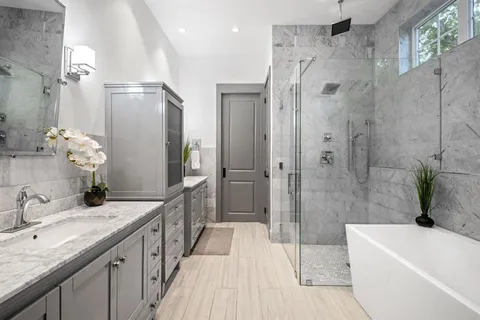 a bathroom with a granite countertop bathtub shower sink mirror and toilet