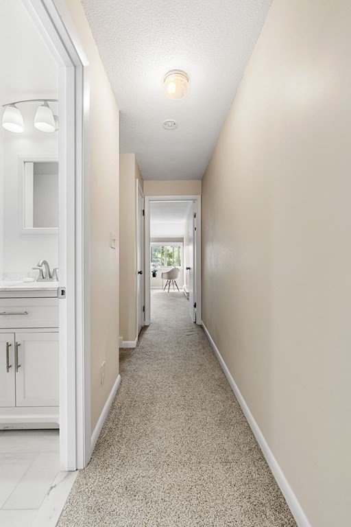 19 Atlantic Road, Unit 12 Gloucester, MA 01930 - Photo 27 of 35 a view of a hallway to a livingroom and a bathroom with sink