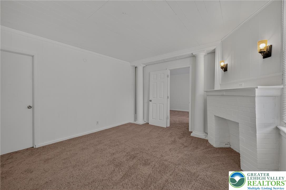 313 Main Street Slatington, PA 18080 - Photo 14 of 73 A cozy interior features plush carpeted floors and a charming brick fireplace with an elegant white mantel.