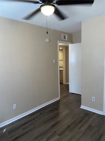 a view of an empty room with wooden floor and closet