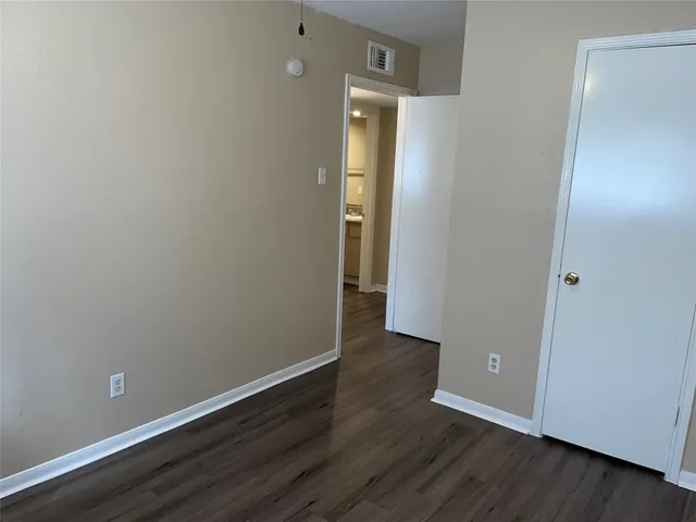 an empty room with wooden floor ceiling fan and windows