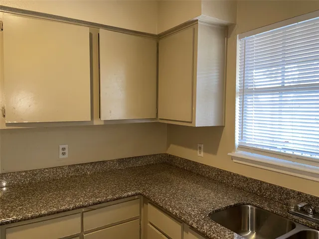 a kitchen with a granite countertop sink and cabinets