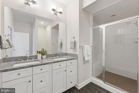 a bathroom with a granite countertop sink a mirror and a shower